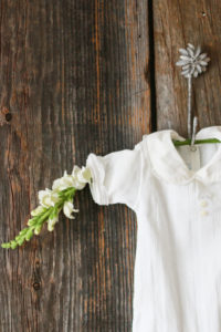 studio wardrobe: white onesie handing on wooden background.
