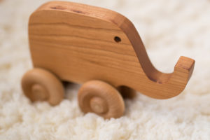 wooden elephant toy on fluffy white rug.