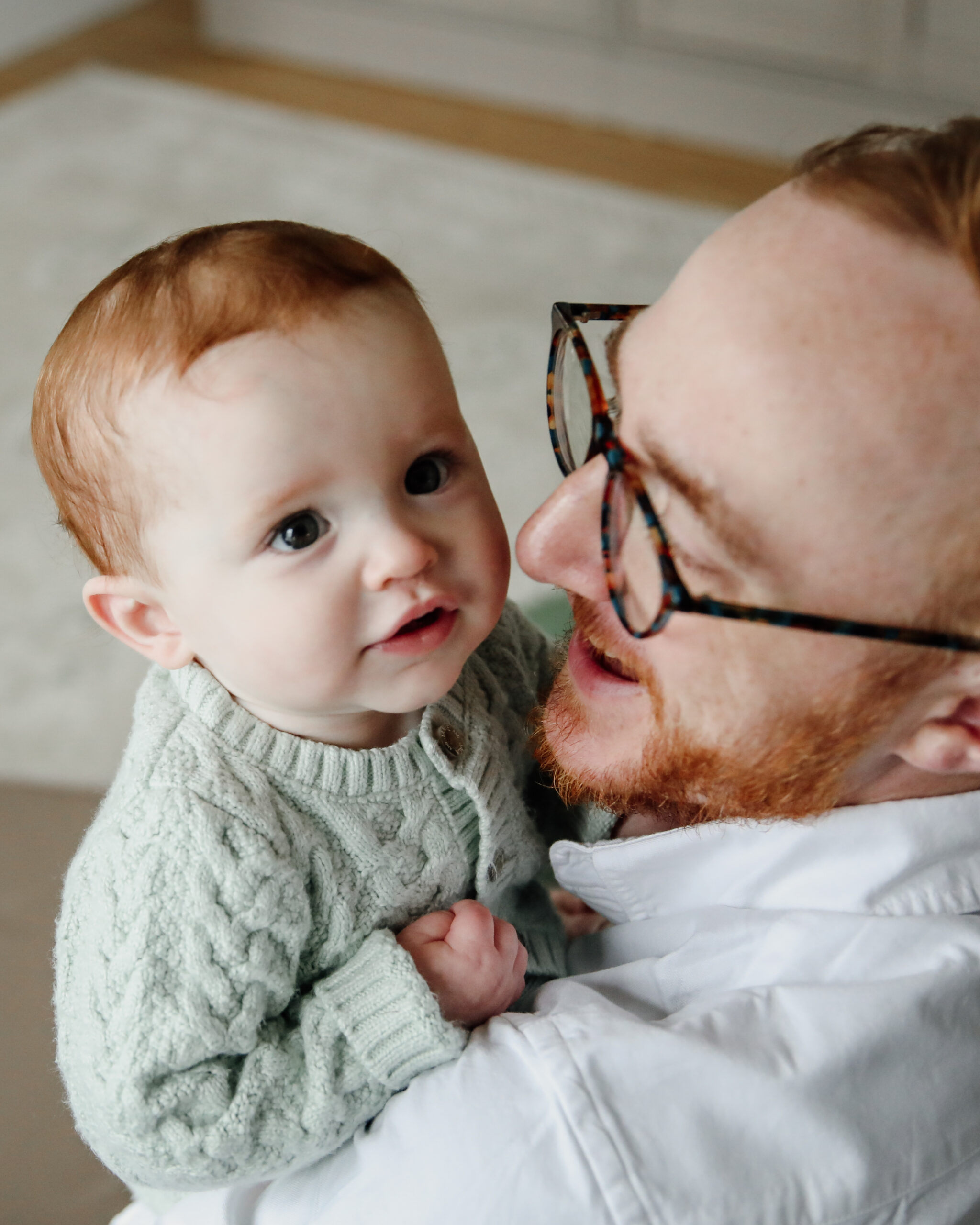dad holding baby up, looking over dad's shoulder