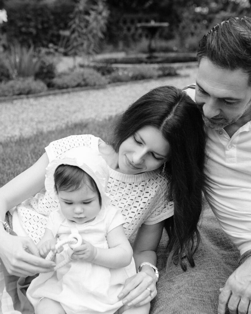 black and white summer family photo of couple playing with baby girl on a blanket.
